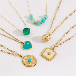 Luxurious gold-plated titanium necklaces with green agate and heart pendants on white fabric