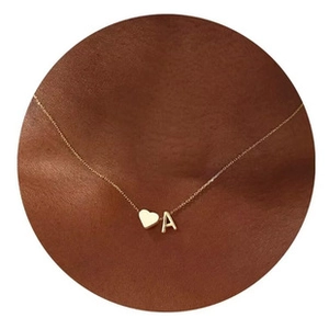 Close-up of gold chain necklace with delicate heart and letter A pendants on model
