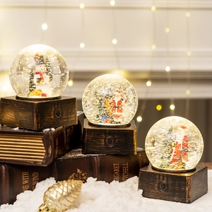 Luminous Christmas water globe with Santa and Snowman figures on dark wood grain base
