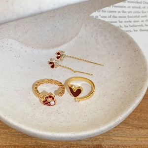 Detail of 18k gold plated ring with red heart pearl and zircon in ceramic tray