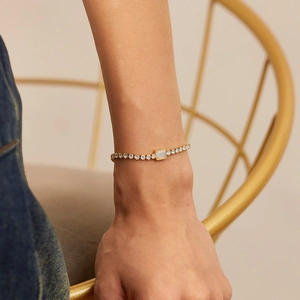 Close-up of gold plated stainless steel bracelet with zircon inlay and white rectangular stone