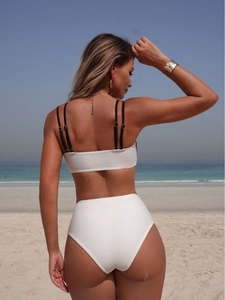 White two-piece bikini with multi-strap bandeau top and high-waist bottoms on beach