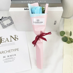Detailed view of a single blue soap rose bouquet in pink wrap with a red ribbon