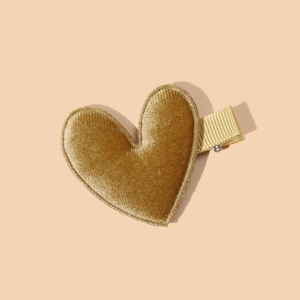 Close-up of a velvet heart hair clip in golden finish with a soft fabric texture
