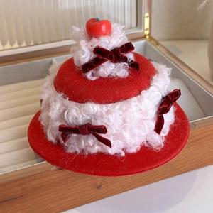 Detailed view of cream cake hair clip with red bows and cherry on wooden jewelry box
