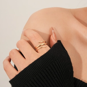 Primo piano di un anello a spirale dorato a tre strati indossato con un maglione nero