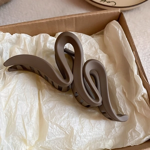 Detail of mocha brown wavy hair claw clip with matte finish in aesthetic packaging