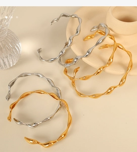Detail view of wavy stainless steel open bangles in gold and silver finishes