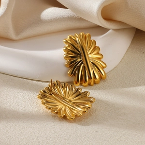Detailed view of gold petal earrings with metallic texture on silk and stone background
