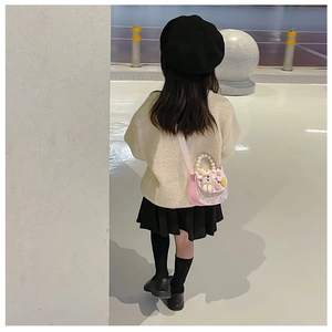 Pink girl's crossbody bag with pearl handle and cute teddy bear seen on a young model