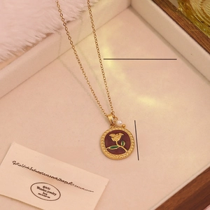 Detail of a stainless steel rose pendant necklace with a pearl on a jewelry box