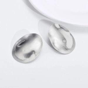 Minimalist irregular oval silver stud earrings with a brushed metal texture finish