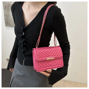 Detail of rose pink crossbody bag with V-quilted texture and gold chain strap