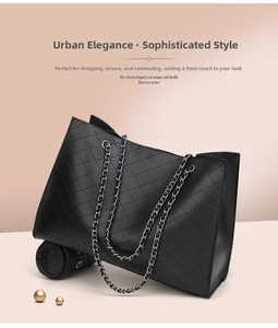 Detail of black quilted tote bag with silver chain strap and lychee texture finish