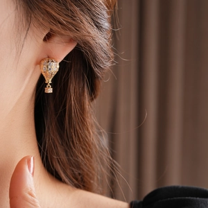 Détail de la boucle d'oreille montgolfière dorée avec zircone portée à l'oreille