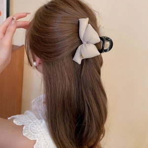 Rear view of model wearing a beige acrylic hair claw clip with a 3D sponge bow accessory