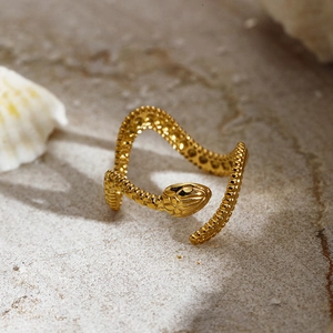 Punk style golden snake open ring with detailed scale texture on a stone background