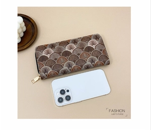 Detail view of long zipper wallet with elegant brown scallop embroidery next to a smartphone