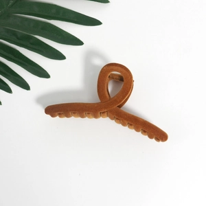 Detail of large camel velvet hair claw clip with flocking texture on white background