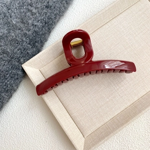 Macro view of burgundy large hair claw clip with glossy finish and golden metal spring