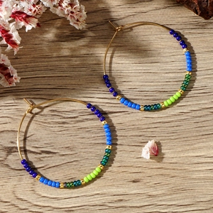 Detail shot of bohemian hoop earrings with colorful beads on a rustic wood background