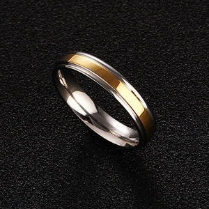 Close-up of a two-tone gold and silver titanium ring on a black textured surface