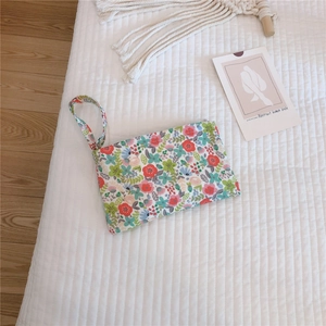 Close-up of cotton mini pouch with floral pattern and fabric handle on white bedding