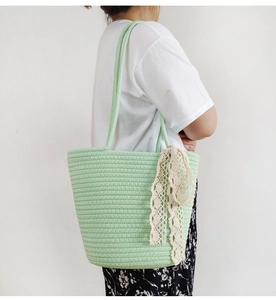 Detail of light green cotton rope woven shoulder bag with white lace bow accessory