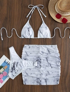 Three-piece marble print bikini set with ruched skirt and halter top on wood background