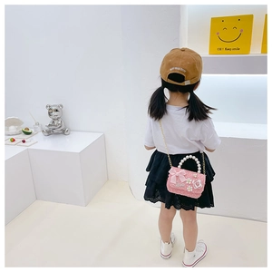 Détail d'un sac à main en tweed rose pour enfant avec poignée en perles et nœud