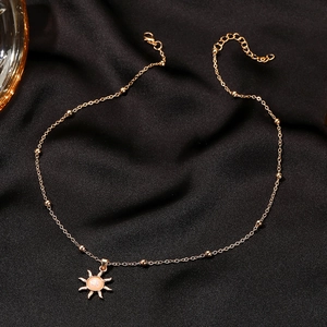 Golden sun pendant necklace with synthetic opal center on elegant black fabric background