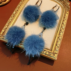 Detailed view of blue pom-pom earrings with rhinestones inside a vintage frame
