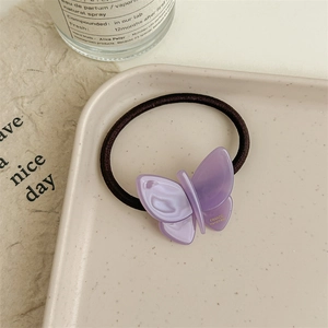 Detail of purple acetate butterfly hair tie with handmade engraving on beige tray
