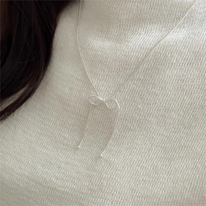 Detail of a 925 sterling silver bow snake chain necklace worn on a white sweater