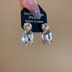 Detailed view of silver stud earrings with rectangular and round cut crystals on card