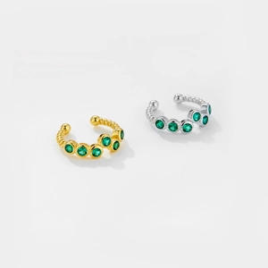 Detailed close-up of gold and silver twisted ear cuffs with green round gemstones
