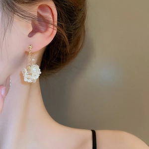 Elegante Blumenohrringe mit Goldkette und weißen Blüten am Modell getragen