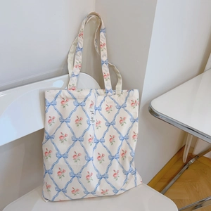 Detail of floral canvas tote bag with blue ribbons and pink roses on a white chair