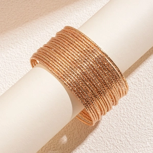 Dettaglio macro di 20 bracciali rigidi dorati strutturati su supporto minimalista
