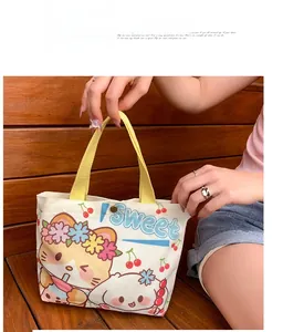 Detail of canvas tote bag with cat print, yellow handles, and metal button closure