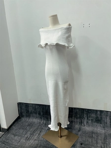 Close-up of white off-the-shoulder knitted maxi dress with ruffled collar and hemline
