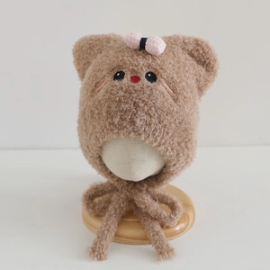 Detail of plush brown kitten ear hat with pink bow and embroidered cat face for kids
