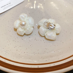 Detailed close-up of cream fabric flower earrings with center pearl and clip-on back