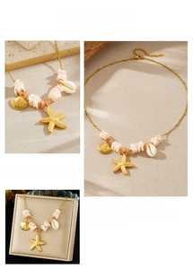 Detail of gold starfish and shell pendant necklace on sandy beach background