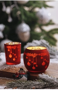 Close-up of red frosted glass Christmas candle holders with gold snowflake patterns