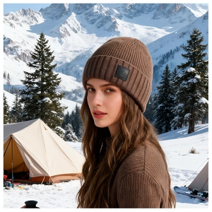 Brown ribbed knit beanie with mountain patch shown in a snowy outdoor camping scene