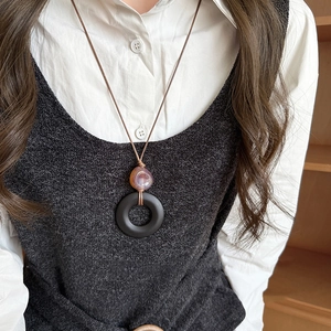 Détail d'un collier ethnique avec anneau en résine sombre et perle d'agate violette