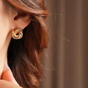 Close-up of model wearing gold twisted hoop earrings with a minimalist metal design