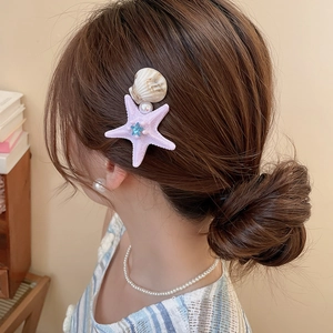 Detail of starfish and shell hair clip with pearls on a side braid hairstyle