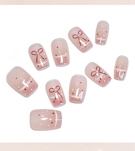 Détail macro de faux ongles œil-de-chat roses avec nœuds rouges et perles blanches
